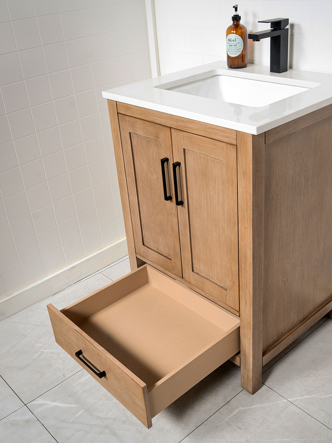 white oak vanity with matte black handles and faucet, bottom drawer and white quartz counter