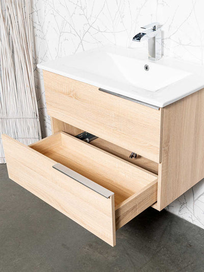 Bottom drawer open on wood grain finish vanity. White ceramic sink and chrome faucet.