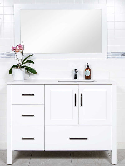 white vanity with sink on the right side. white wood framed mirror