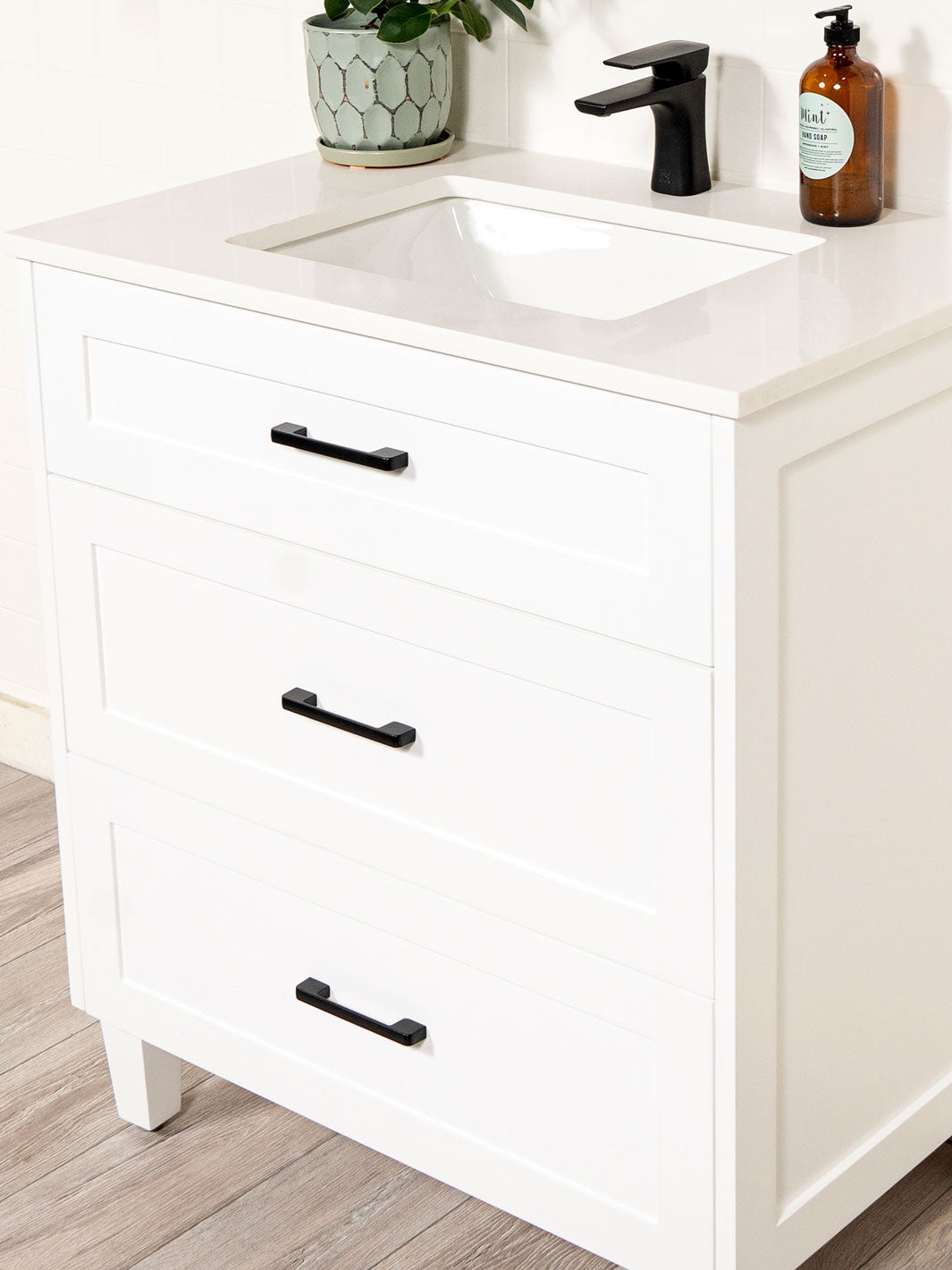 cabinet with black pulls and black faucet