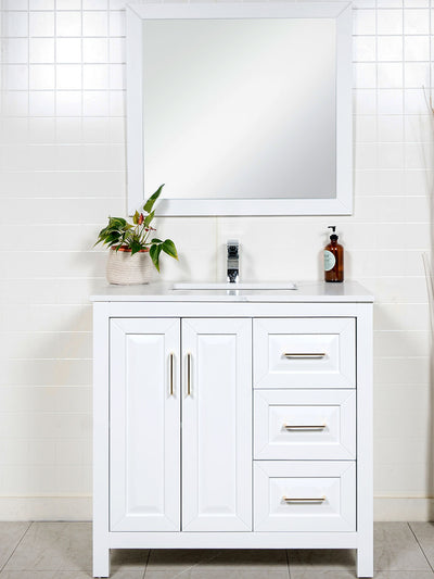white vanity with 3 drawers on the right. White counter. black framed mirror