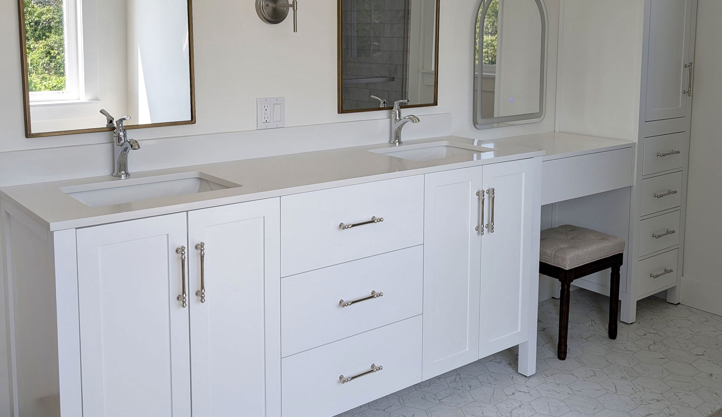 A white double-sink bathroom vanity with three drawers, silver handles, a make-up table and matching linen cabinet