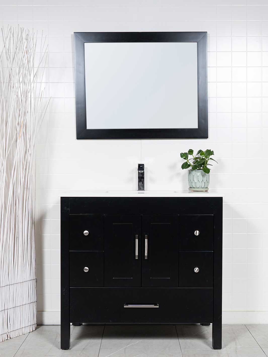 Black bathroom vanity with 5 drawers and a cupboard beneath the sink. there is a black wood framed mirror and a white quartz counter